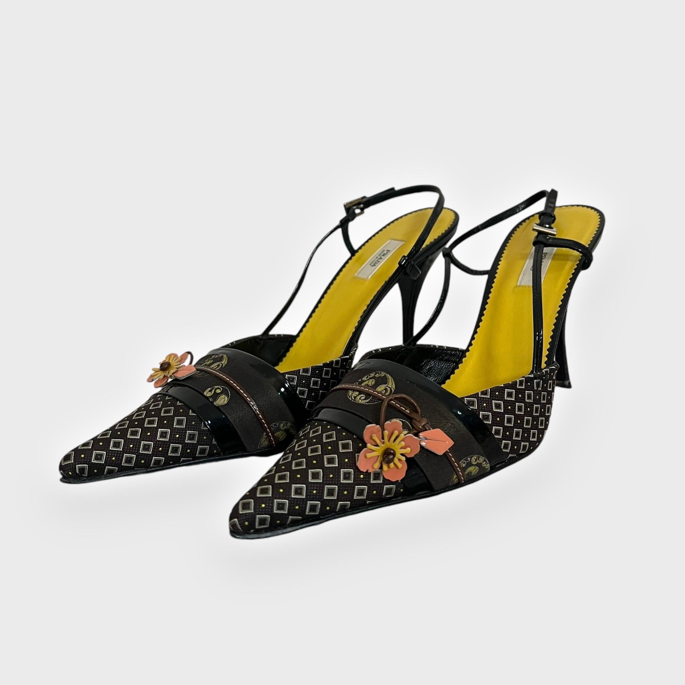 These vintage Prada slingback heels from the Spring/Summer 2003 collection beautifully incorporate an Asian-inspired design. The pointed-toe silhouette is adorned with intricate kimono-inspired patterns and charming 3D floral appliqués in orange,