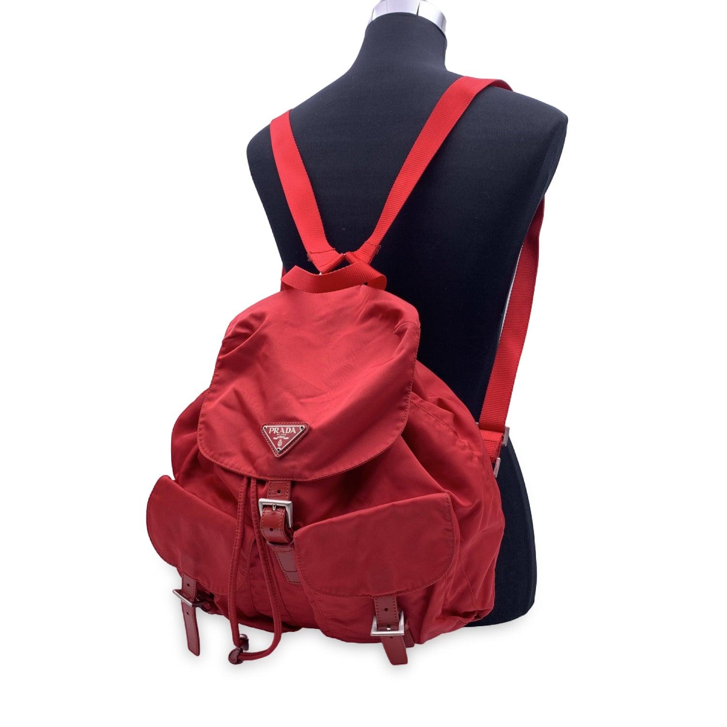 Prada Vintage Red Nylon Canvas Backpack. Nylon with silver hardware. Adjustable straps. Drawstring top closure. Flap top with magnetic button closure with PRADA triangle logo plaque on the flap. Double exterior pockets. PRADA fabric lining with 1