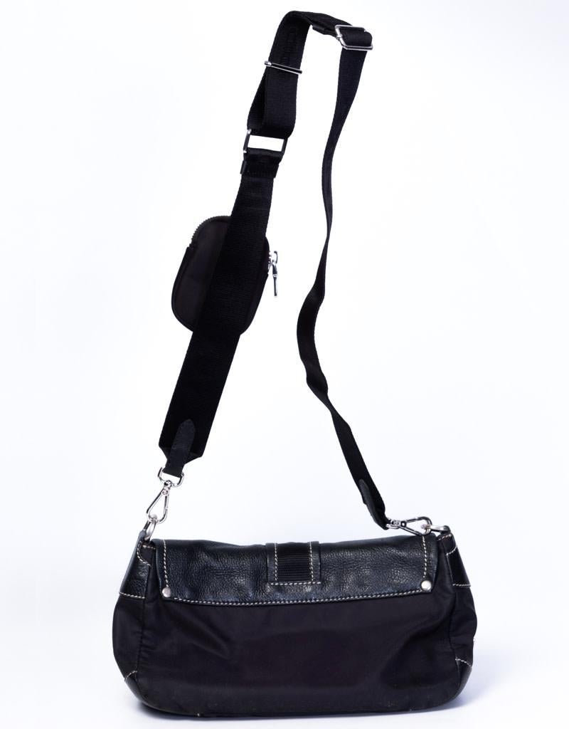 This bag features a black nylon body with leather trim and a front buckle to secure the top flap with magnetic snap closure. This bag comes with the Prada Re-edition ’05 attachable strap for shoulder carry. 

COLOR: Black
MATERIAL: Leather and