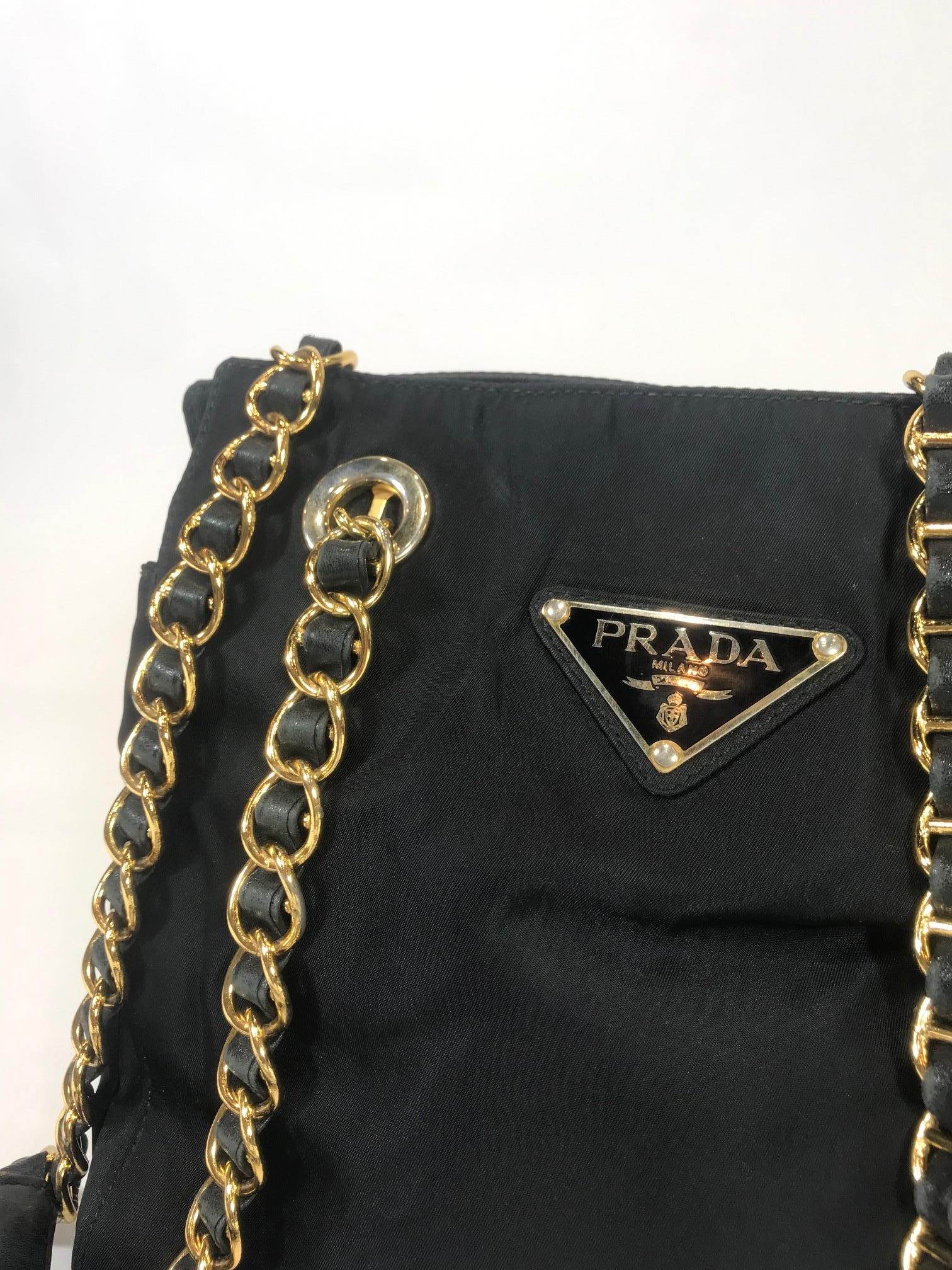 Black nylon. Gold-Tone hardware. Dual chain and leather shoulder straps. Prada logo at front. Three interior compartments. Middle compartment has top zippered closure. One interior zippered pocket.
