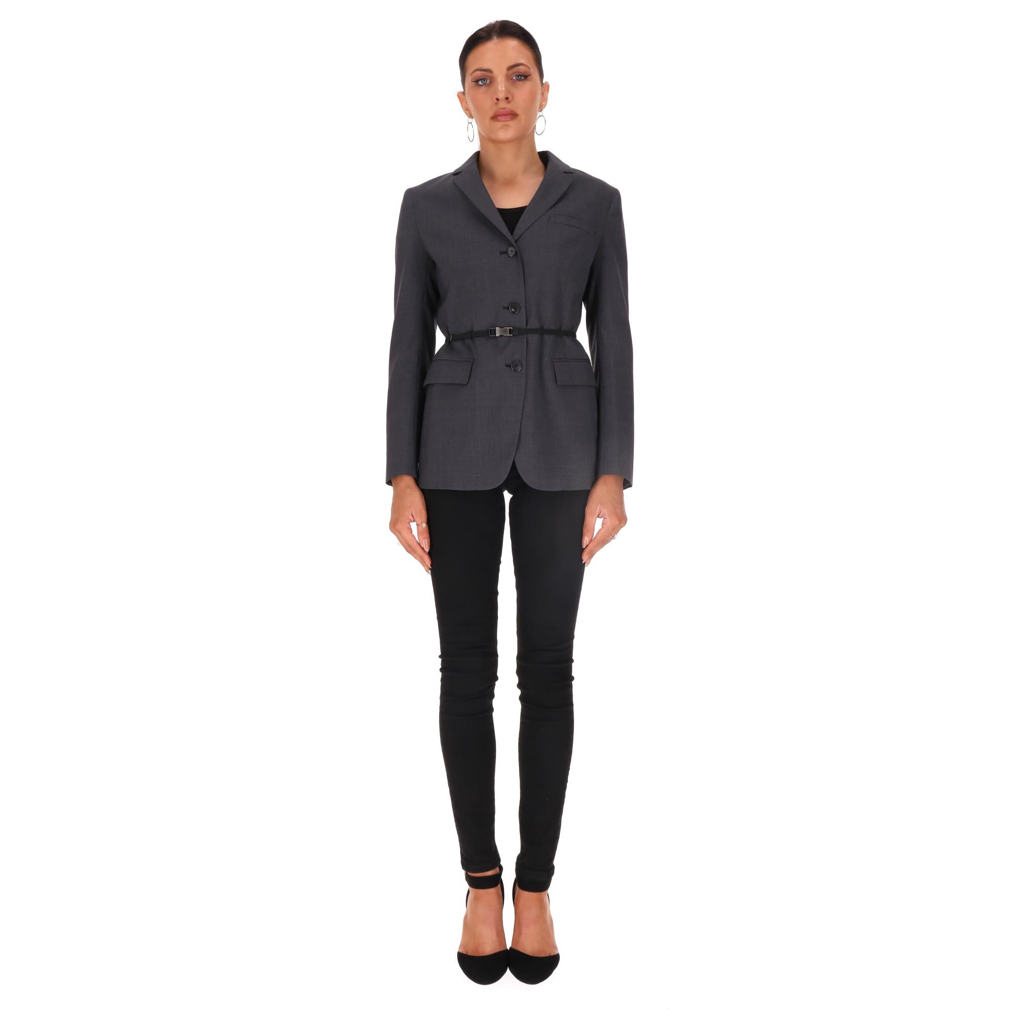 Blazer/veste ceinturée en gabardine de laine vierge Prada. Taille 40IT

Veste gris foncé entièrement réalisée en laine vierge avec poches à rabat sur le devant.

Détaillée avec une ceinture en nylon noir ornée d'un clip en métal sur lequel est gravé
