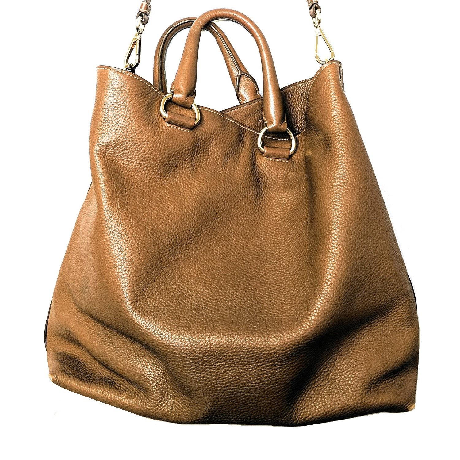 This stylish tote is crafted of finely textured brown vitello daino calfskin leather. The bag features leather rolled top handles with polished brass hardware and an optional shoulder strap. The top opens to a wide and spacious matching Prada