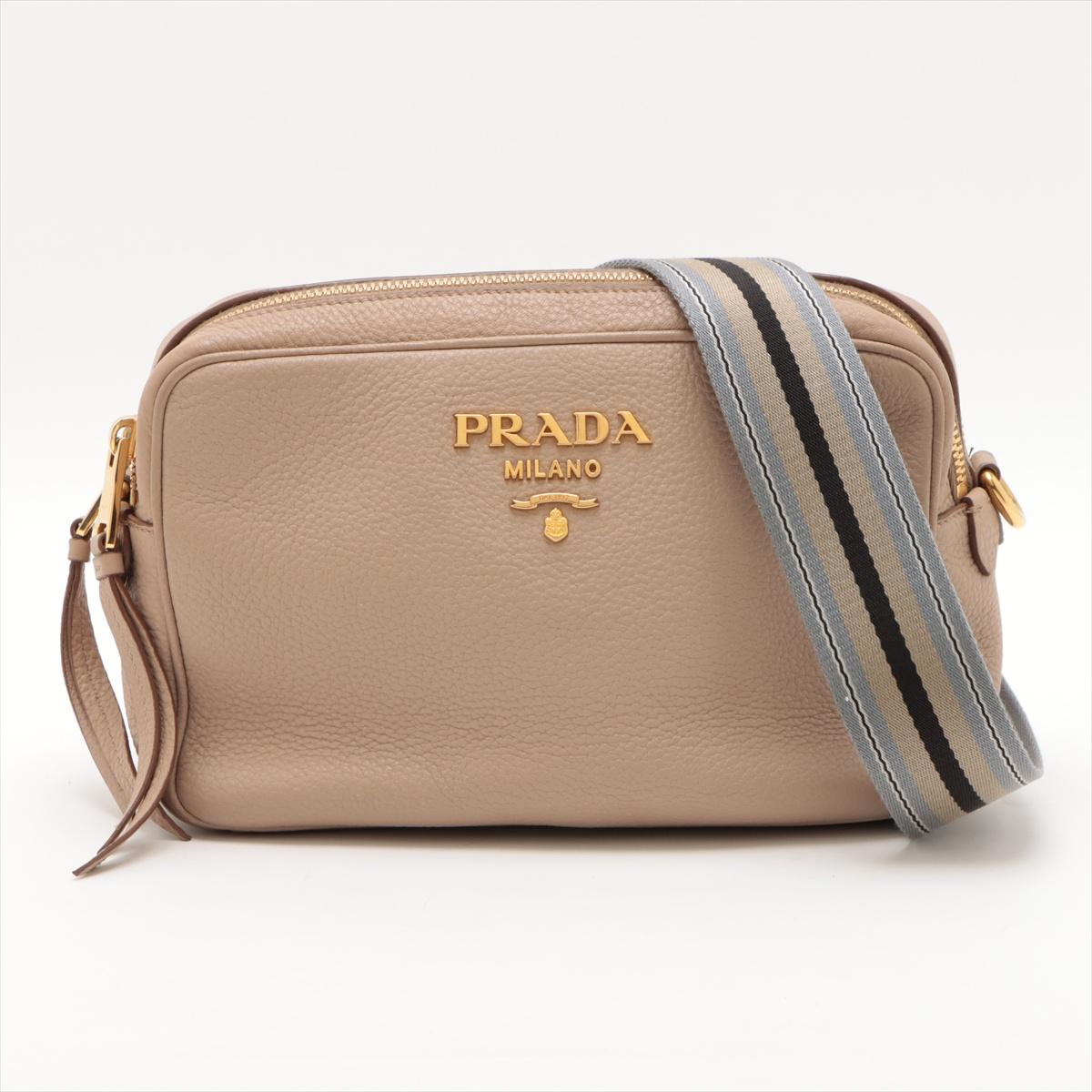 The Prada Vitello Daino Leather Camera Bag in Beige is a chic and versatile everyday bag, crafted from supple and durable Vitello Daino leather known for its soft, pebbled texture. The minimalist yet elegant design is complemented by the signature