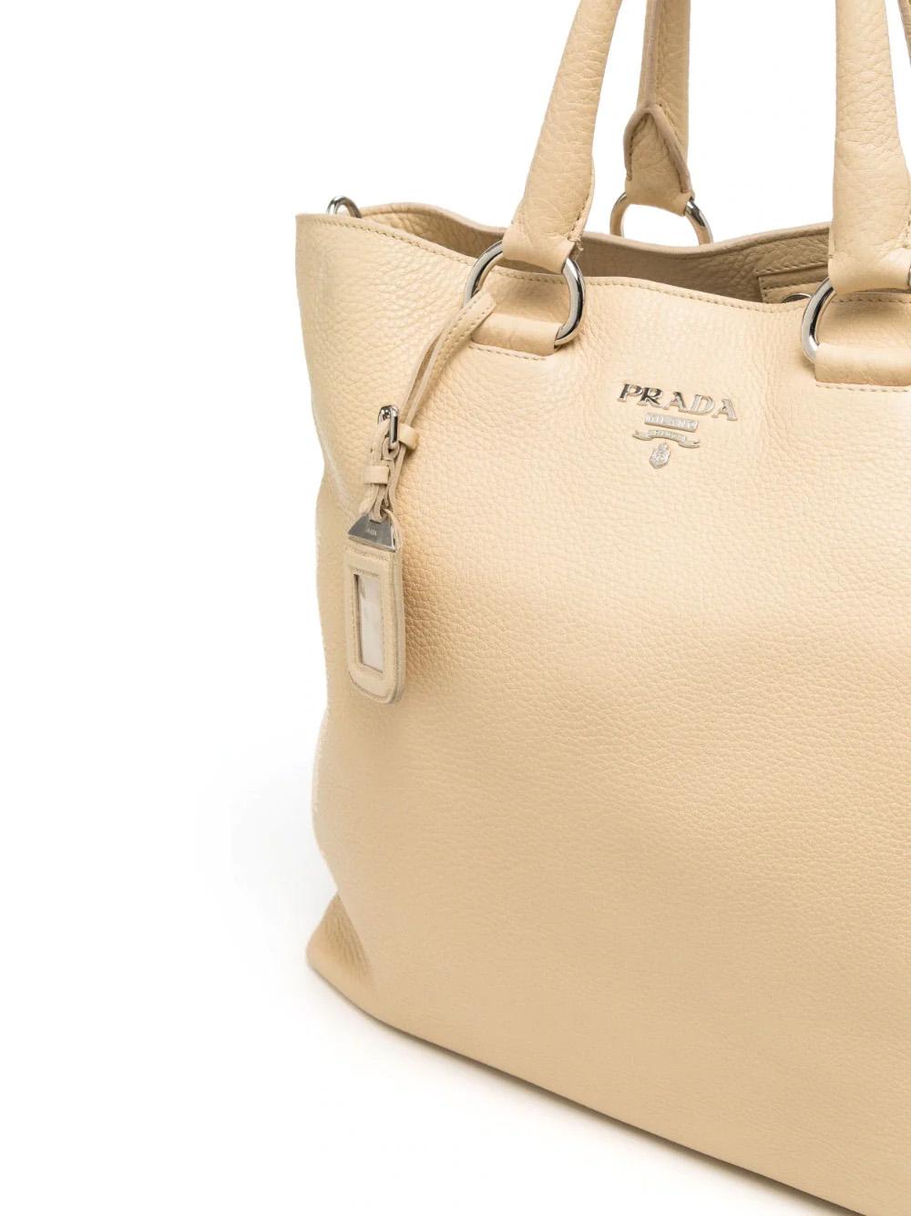 This Italian-made Prada tote bag is crafted from luxurious Daino leather with a unique grained texture. It features two rolled top handles, a detachable shoulder strap, a magnetic fastening, an internal zip-fastening pocket, an internal logo patch,