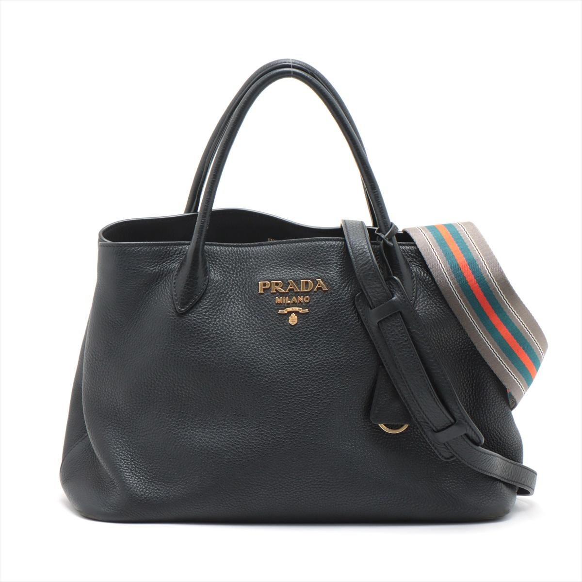 The Prada Vitello Daino Leather Two-Way Handbag in Black offers both sophistication and versatility. Crafted from the distinctive Vitello Daino leather known for its pebbled texture, the bag exudes a timeless elegance in classic black. The two-way