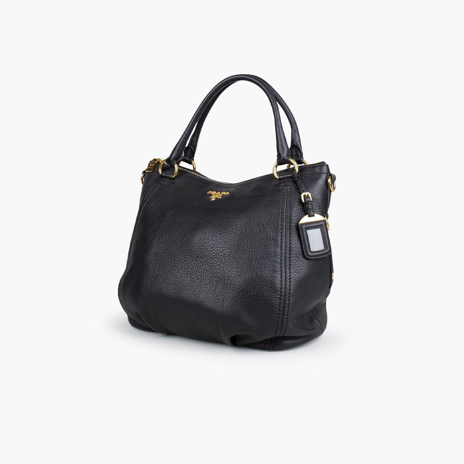 Black Vitello Daino leather Prada shoulder bag with

– Gold-Tone hardware
– Dual rolled top handles
– Single adjustable flat shoulder strap
– Logo hardware embellishment at front
– Protective feet at base, three interior compartments; one with zip