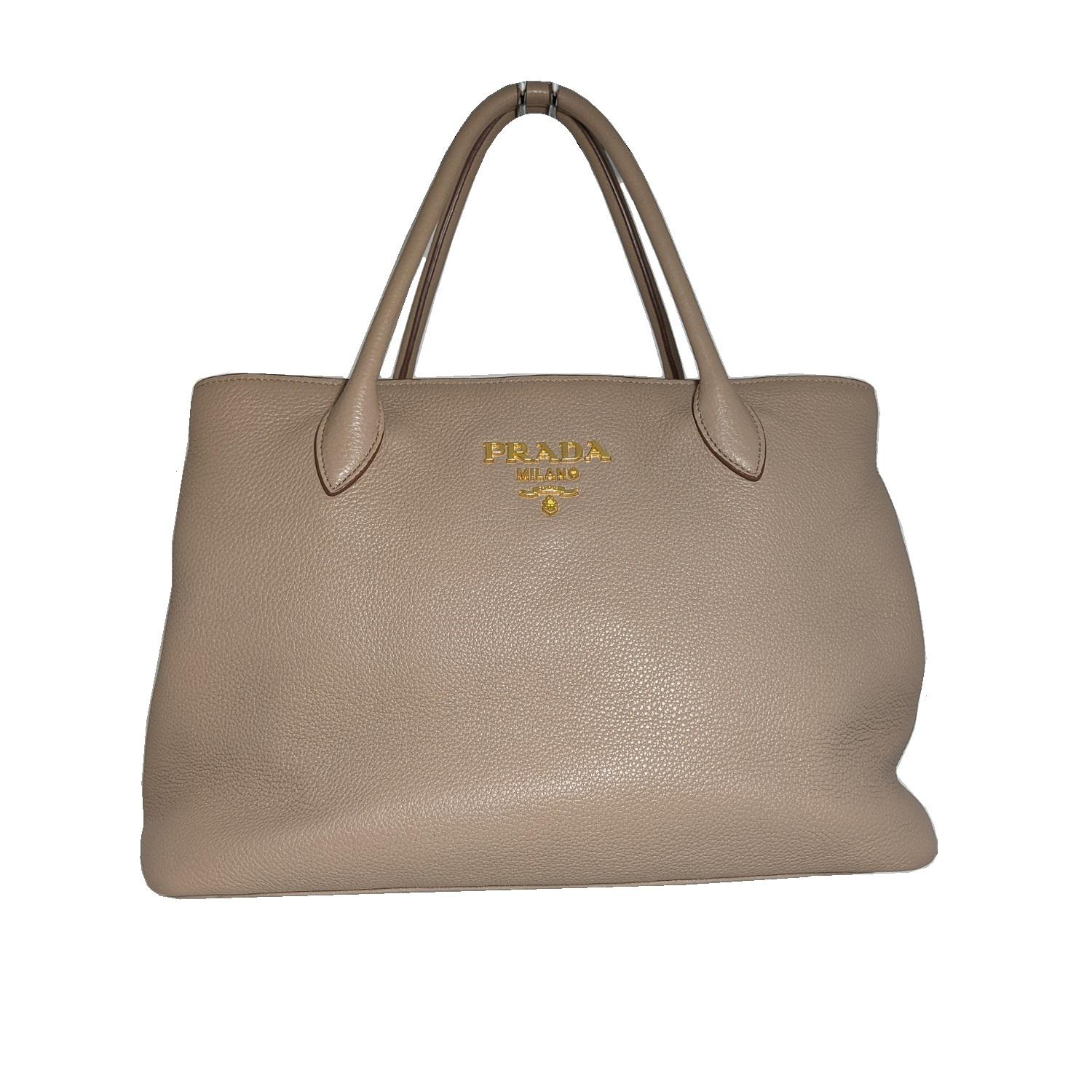 The Prada Pebbled Leather Vitello Daino Tote Bag BN2579 is one sophisticated piece. This durable and spacious tote has the capability to hold all your daily essentials and more. It is made of gorgeous cameo beige pebbled Daino calfskin leather with