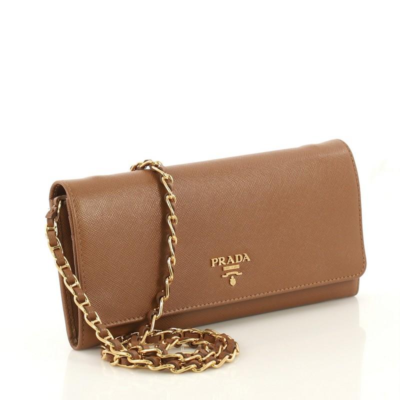 This Prada Wallet on Chain Saffiano Leather, crafted from brown leather, features woven-in leather chain strap, raised Prada logo, and gold-tone hardware. Its dual button snap closure opens to a brown leather interior with multiple card slots and