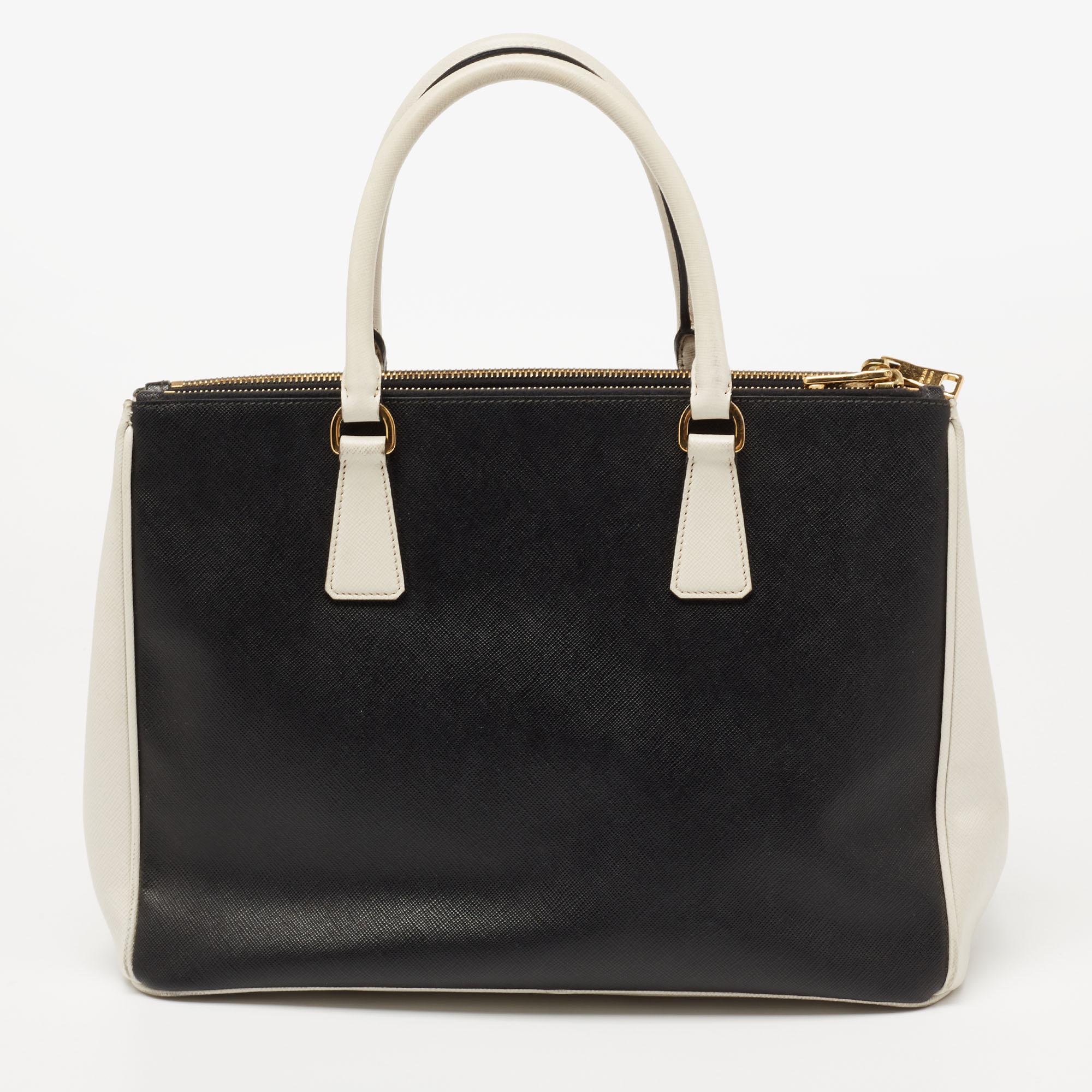 Grand in shape and design, this Double Zip tote by Prada will be a loved addition to your closet. It has been crafted from Saffiano Lux leather and styled minimally with gold-tone hardware. It comes with two top handles, two zip compartments, and