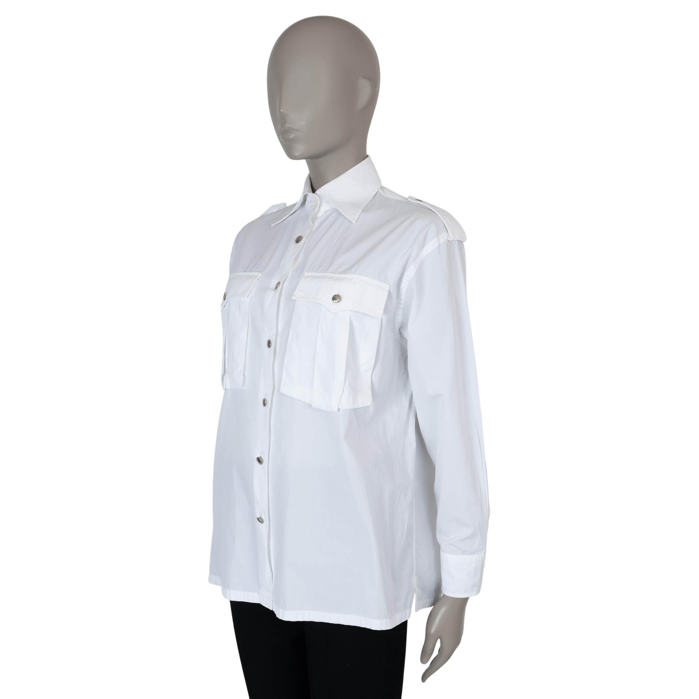 This 100% authentic Prada button-up shirt in white poplin cotton redefines classic tailoring with an oversized silhouette and slightly dropped shoulders. Designed with exaggerated military-inspired details, including epaulettes and front flap