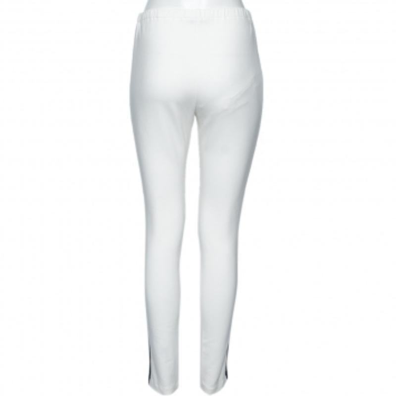 Spend the day comfortably and stylishly with these track pants from the House of Prada. They are made from white cotton fabric, with contrasting trim detailing on their sides. They feature a comfortable well-fitted shape. These Prada pants are a