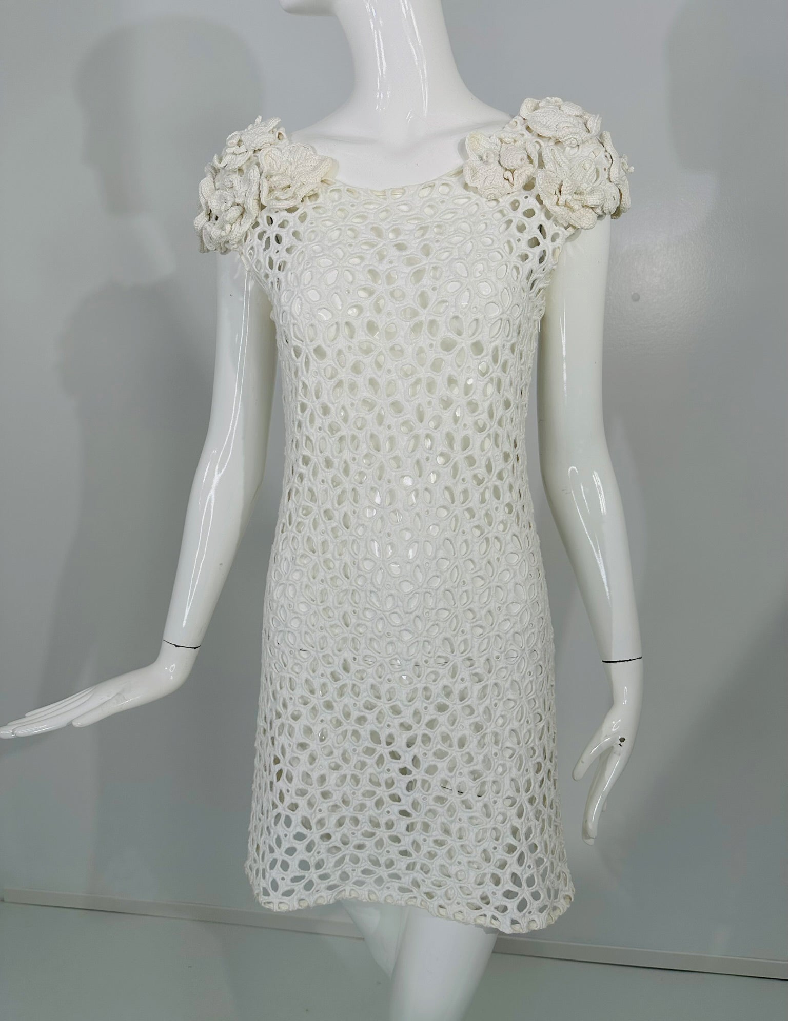 Prada white cotton floral eyelet mini dress with chunky floral   crochet cap shoulders. Sleeveless A line mini dress is heavily embroidered all over, white satin stitch embroidery outlines each little flower petal. Each shoulder is a cluster of