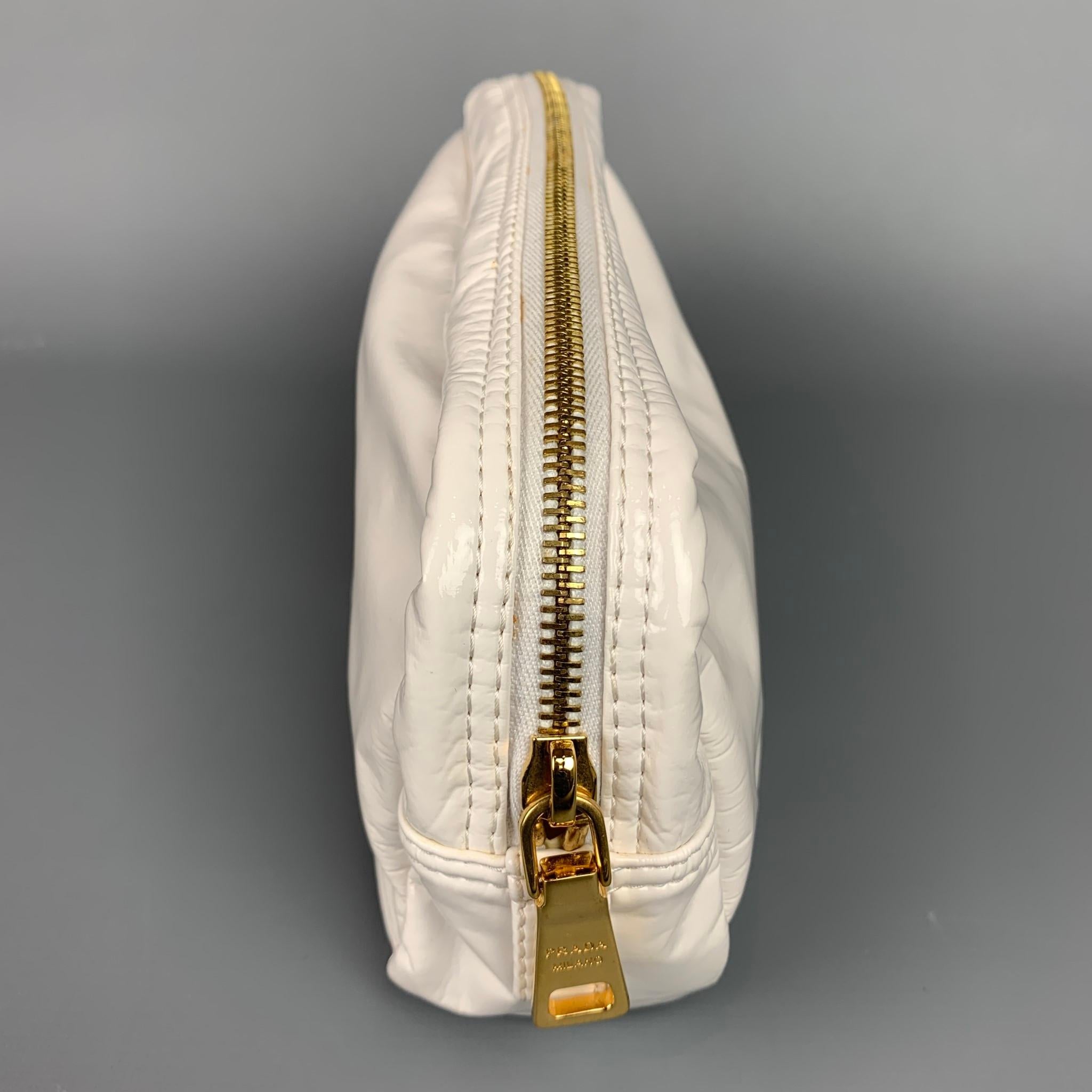 PRADA pouch comes in a white faux patent leather featuring gold tone hardware and a zipper closure.

Very Good Pre-Owned Condition.

Measurements:

Length: 12 in.
Width: 2 in.
Height: 4.5 in.  