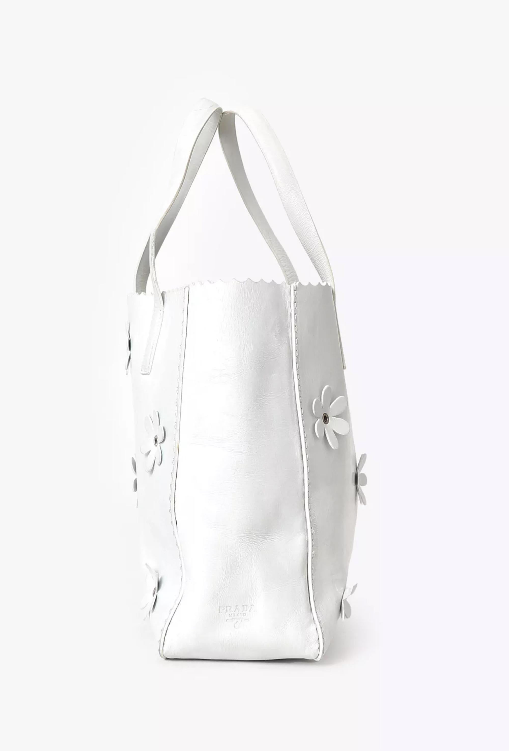 Sac à main en cuir de veau souple Prada White Floral Shopper avec détails floraux sur le devant et le dos, doublure en cuir, ferrures argentées, anses supérieures.
Circa 1999. 100% cuir
En bon état vintage. Fait en Italie.
Longueur : 24 cm (9,4