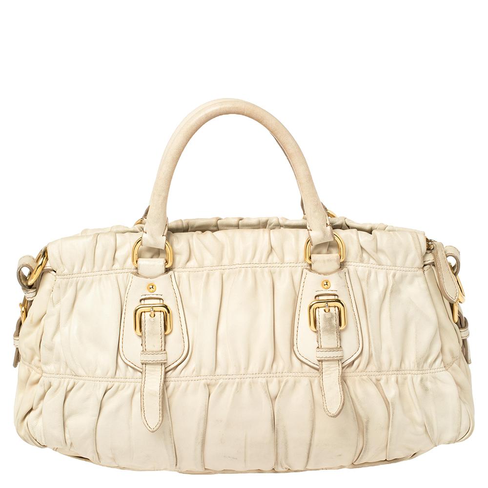 With a bag as classy and stylish as this one from Prada, you are sure to make a lasting impression! The white bag is crafted from leather and features a gathered exterior. It has been styled with gold-tone buckle details, dual top handles, and a top