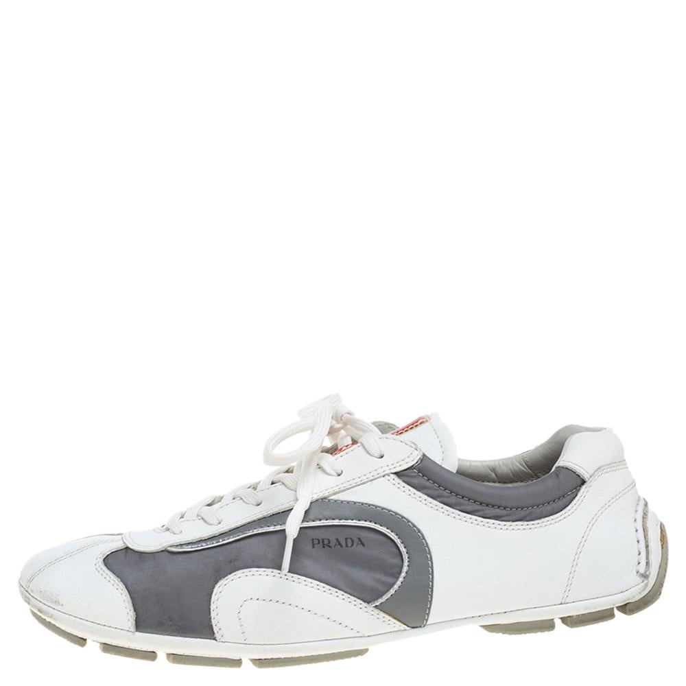 Fall in love with casual wear every time you step out in these sneakers from Prada. They've been crafted from white leather and grey nylon and styled with lace-ups on the vamps and the brand label on the tongues. The sneakers are endowed with