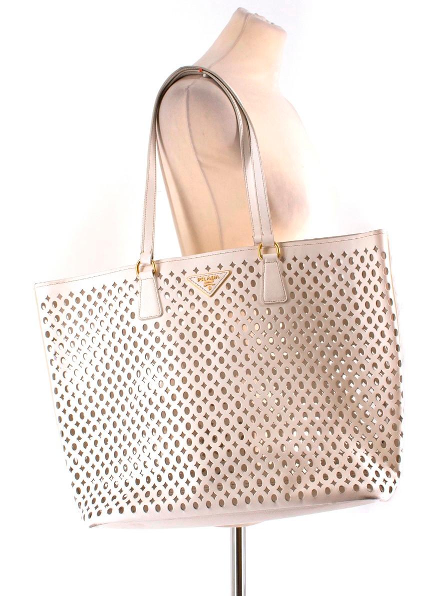 Prada White Laser Cut-out Shoulder Tote

- Spacious open shoulder tote
- White laser cut patterned leather
- 2 long shoulder straps
- Gold-tone hardware 
- Leather and metal branding plaque on front
- Comes with a white matching zipped pouch inside