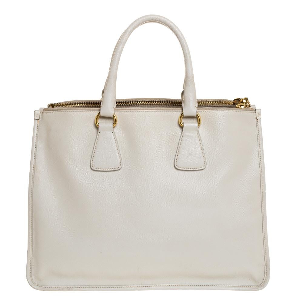 Feminine in shape and grand in design, this Double Zip tote by Prada will be a loved addition to your closet. It has been crafted from leather and styled minimally with gold-tone hardware. It comes with two top handles, two zip compartments and a