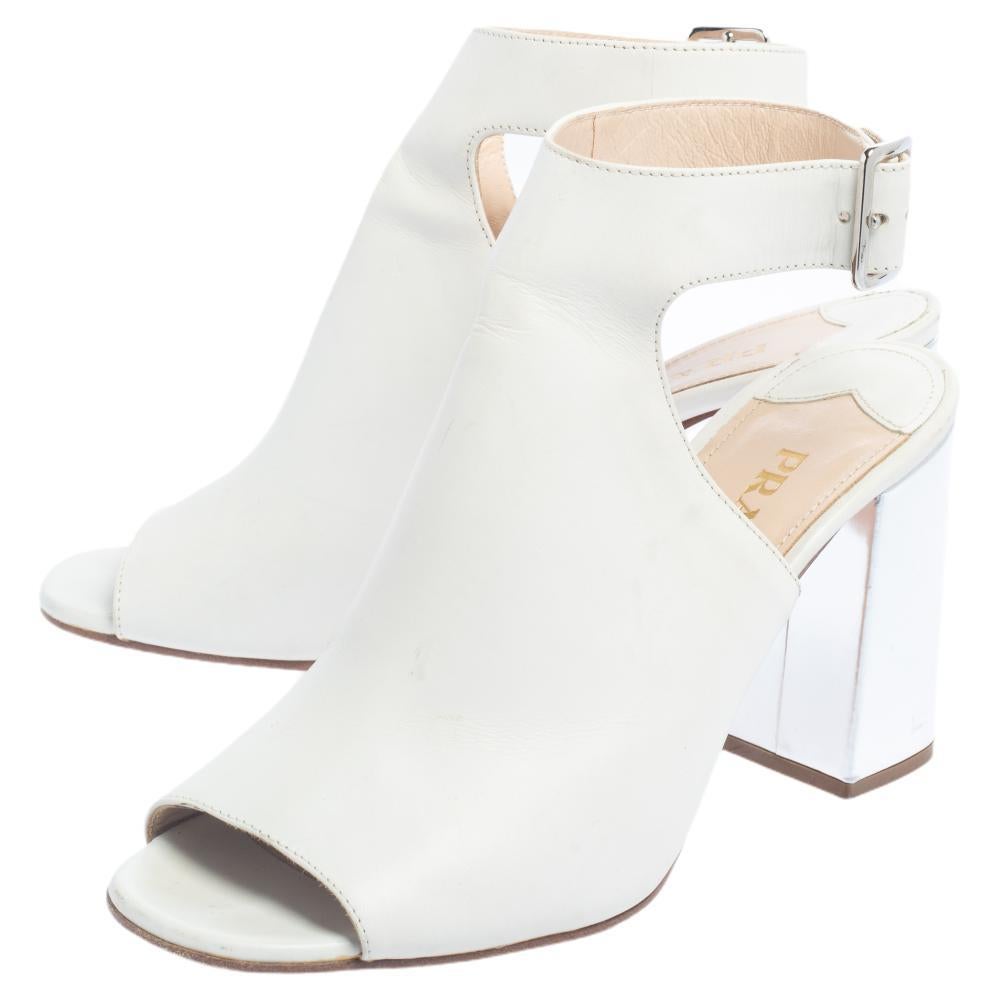 Receive enduring comfort and style with these sandals from Prada. Fashioned in white leather, the sandals come with peep toes, open counters, buckle ankle fastening, and 8.5 cm heels.

