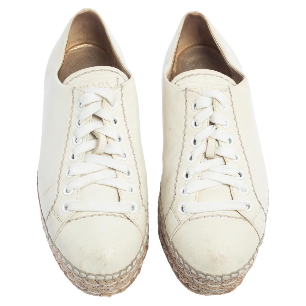 Diese mühelos schicken und stilvollen Sneakers von Prada sind das, was Ihrer Garderobe die ganze Zeit gefehlt hat! Die Sneaker sind aus weißem Leder gefertigt und werden mit Schnürsenkeln befestigt. Bequeme Einlegesohlen und Espadrille-Plateaus