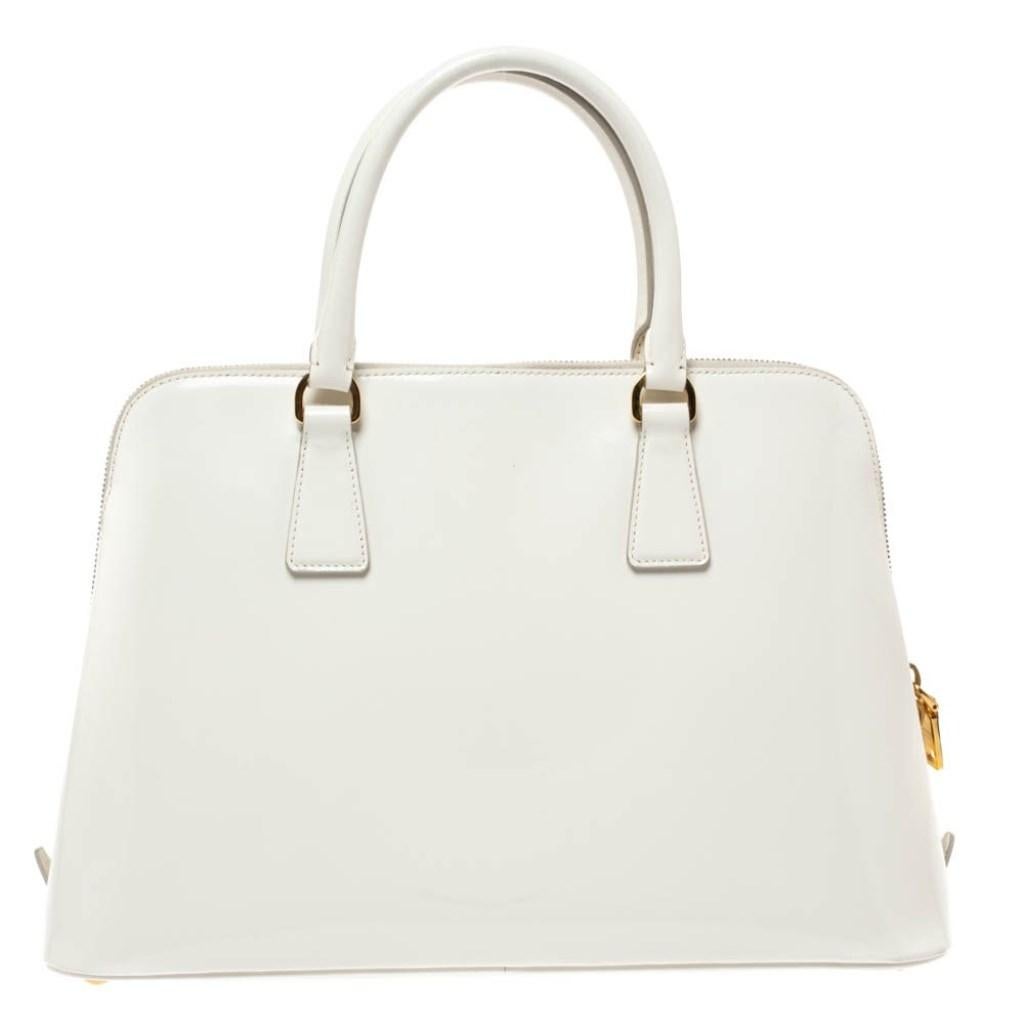 This stunning Promenade is high on appeal and style. Dazzling in white, the bag is crafted from patent leather and features two handles. The zip closure leads way to a nylon interior with enough space for your essentials and the bag is complete with