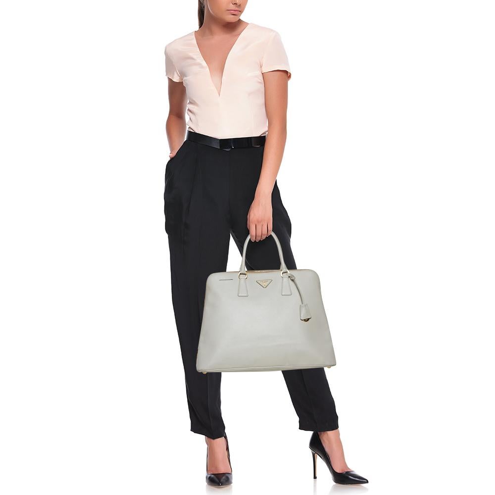 La borsa Dome di Prada è elegante nei suoi dettagli e nella sua struttura. Realizzata in pelle Saffiano Lux, è impreziosita da un logo Prada in oro sul davanti e sorretta da due manici per la tua comodità. Questa elegante borsa è abbastanza capiente