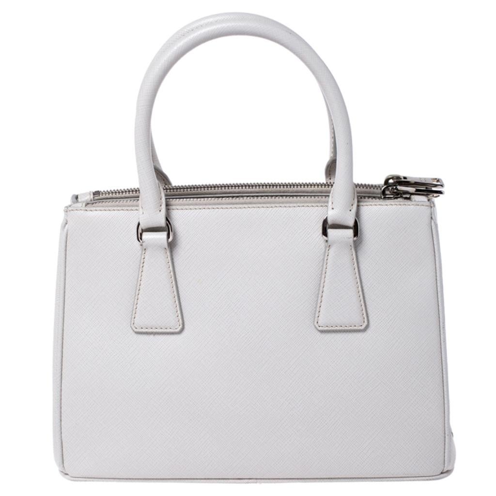 Feminine in shape and grand on design, this Double Zip tote by Prada will be a loved addition to your closet. It has been crafted from leather and styled minimally with silver-tone hardware. It comes with two top handles, two zip compartments and a