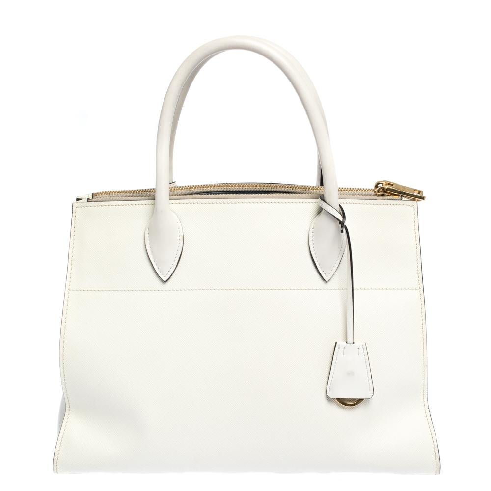 Prada's Paradigme tote exudes appeal through a structured shape and minimal detailing. Crafted from Saffiano Lux leather, the tote in white has two handles, a shoulder strap, triangular side gussets and a spacious interior. Make it yours