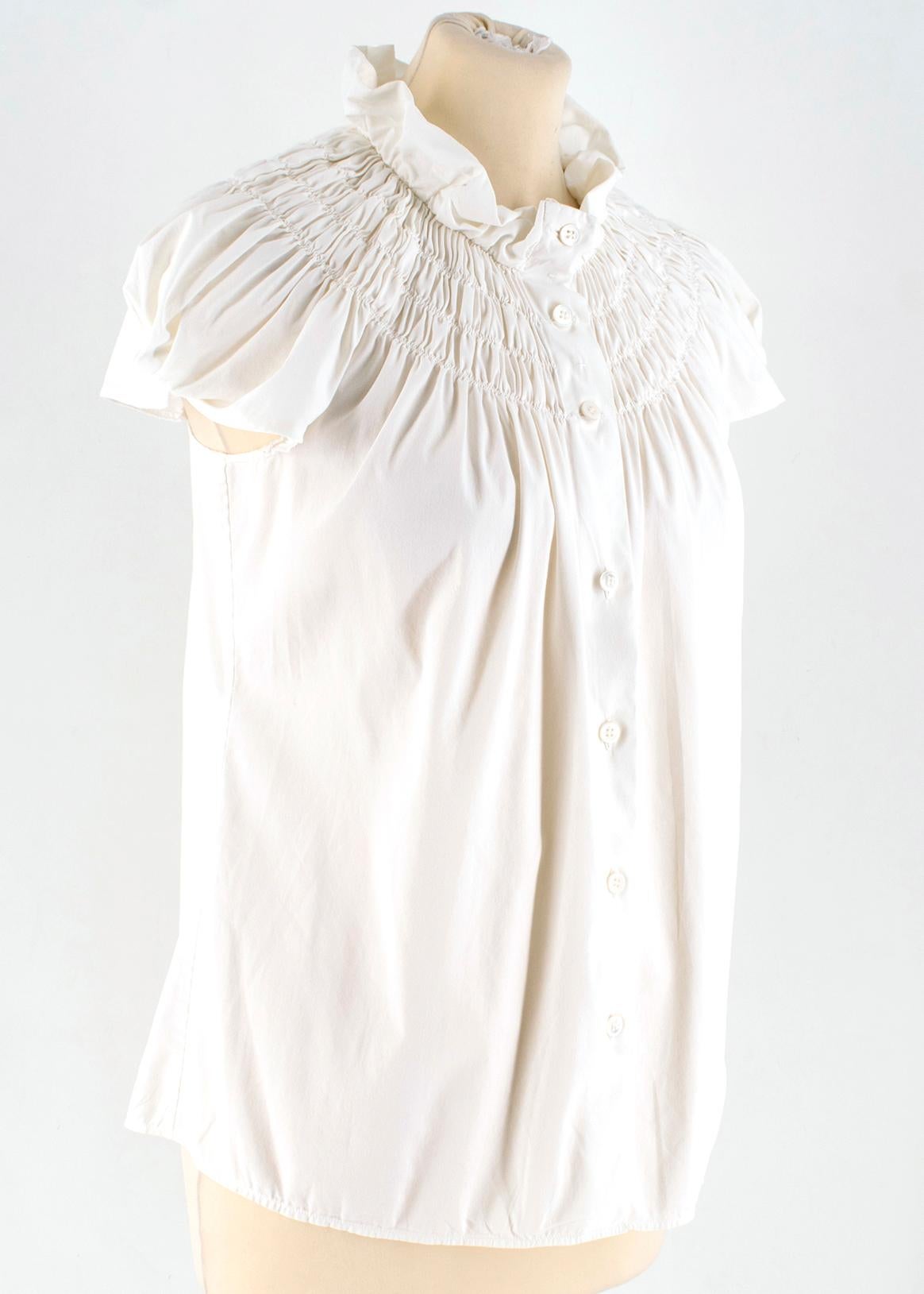 Prada White Smocked-Neck Blouse

- Off-white, poplin
- Ruffled stand collar, capped sleeves 
- Smocked neckline 
- Centre-front button fastening

Please note, these items are pre-owned and may show some signs of storage, even when unworn and unused.
