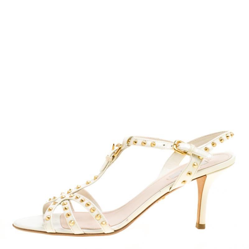 Prada's sandals are embellished with gold-tone studs all over the strappy uppers making the pair look both feminine and glamorous. The clean white hue of these sandals, crafted from patent leather, gives them a refreshing touch. The 8.5 cm high