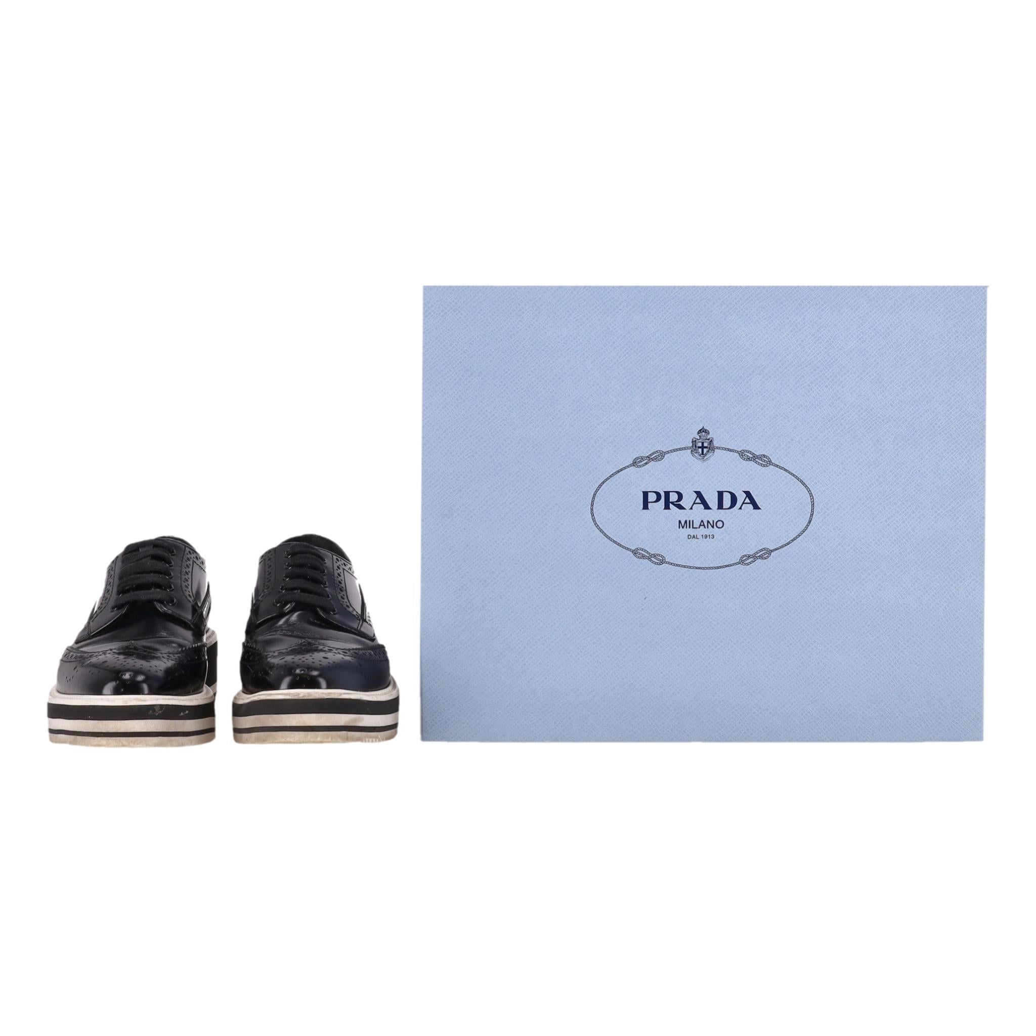 Prada Wingtip Leder Plateau Brogues

Schwarze Brogues zum Schnüren aus hochglänzendem Spazzolato-Leder mit durchgehenden Flügelspitzen-Details.

Mit mandelförmiger Zehenpartie und schwarz-weiß gestreiftem Plateau.

Futter und Innensohle aus