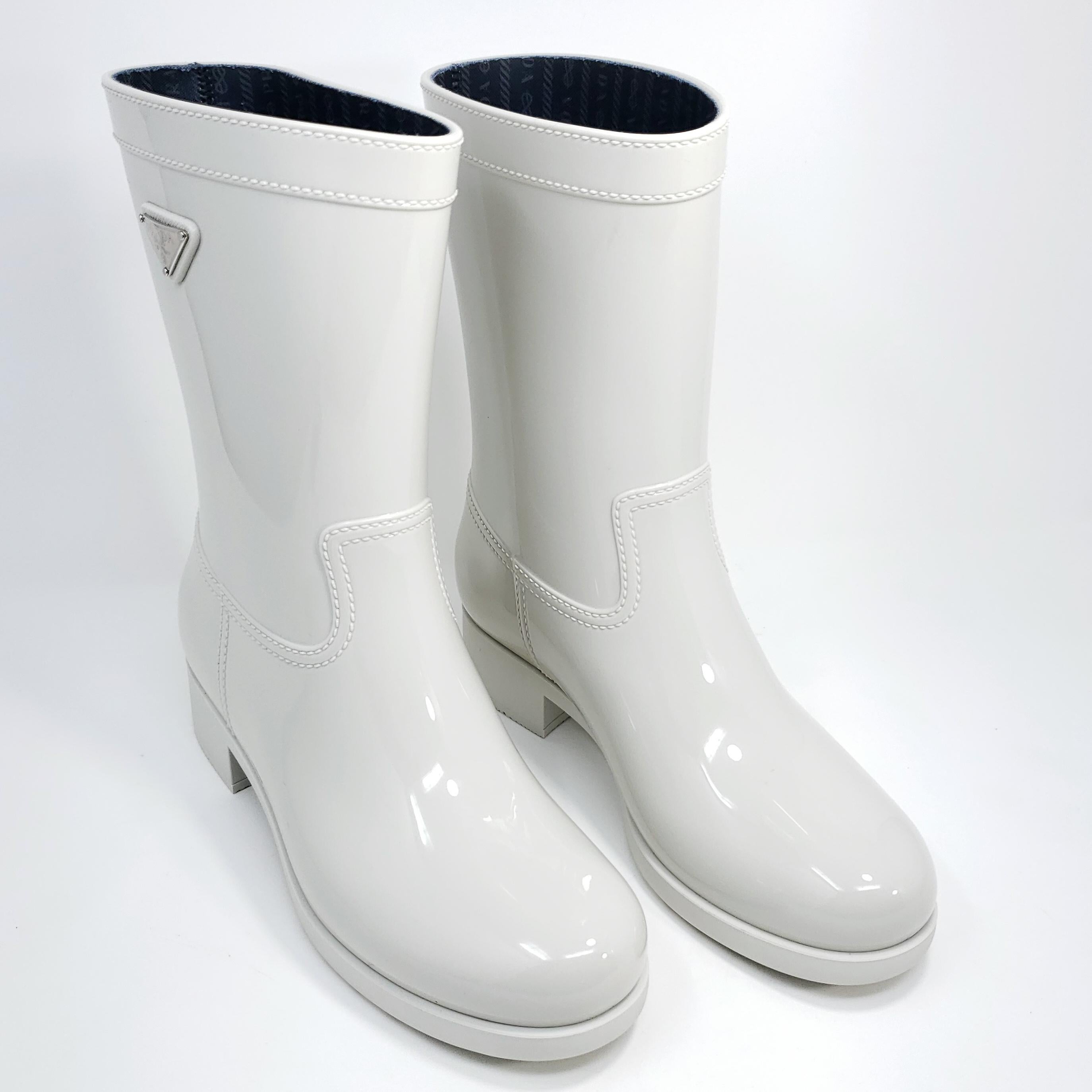 Bottes de pluie Prada élégantes en blanc talco, dotées d'une tige en caoutchouc sport et d'un intérieur doublé de tissu, ainsi que d'une plaque de logo Prada en métal argenté sur le côté. Fabriquées en Italie.

Non porté, livré avec sa boîte