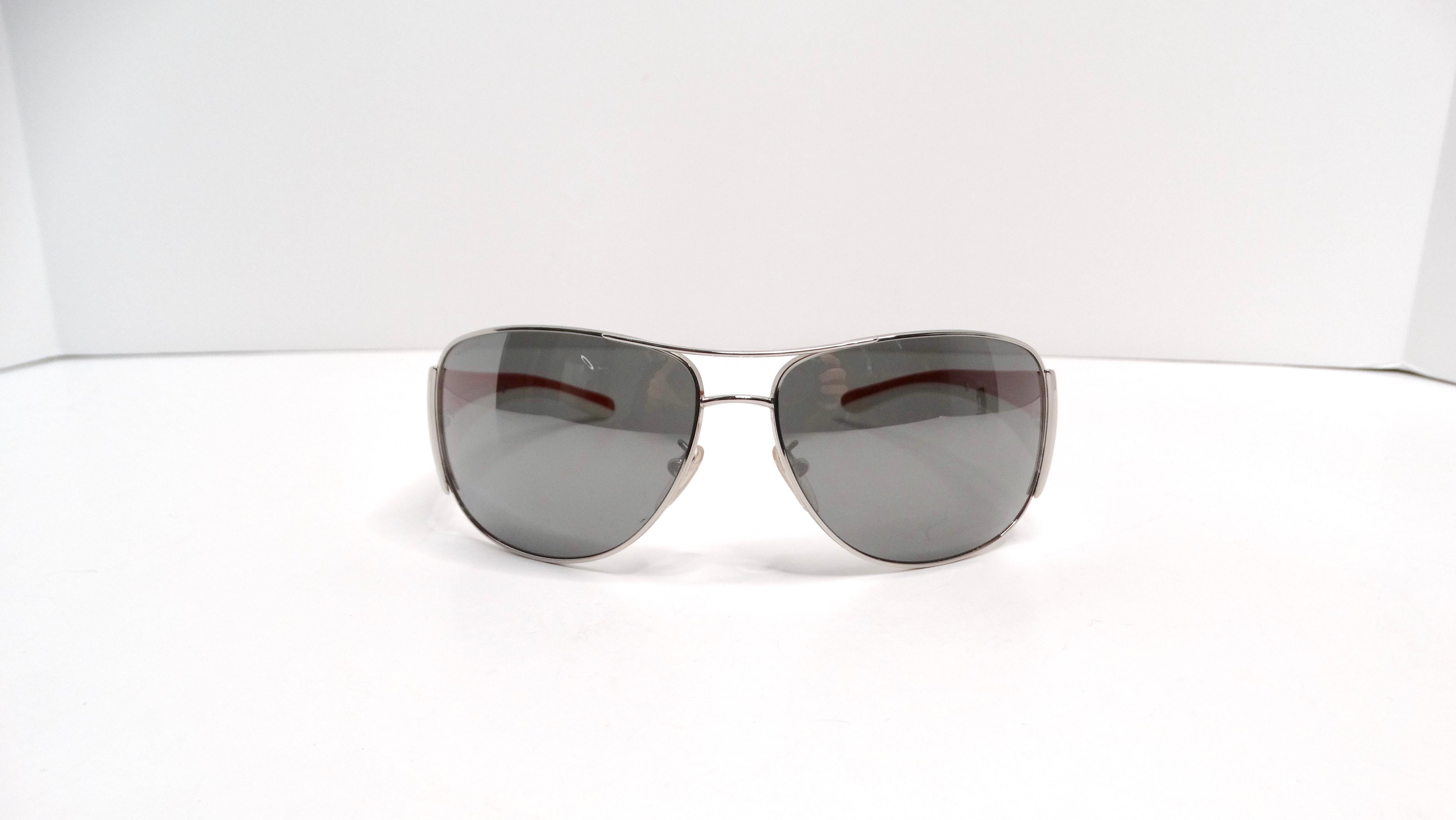 The Prada Circa Y2K Sport Aviator Mirrored Red & White Sunglasses are a striking blend of chic and sporty flair, making them a must-have accessory for fashion enthusiasts. Their mirrored lenses offer a cool and sophisticated look, while the red and