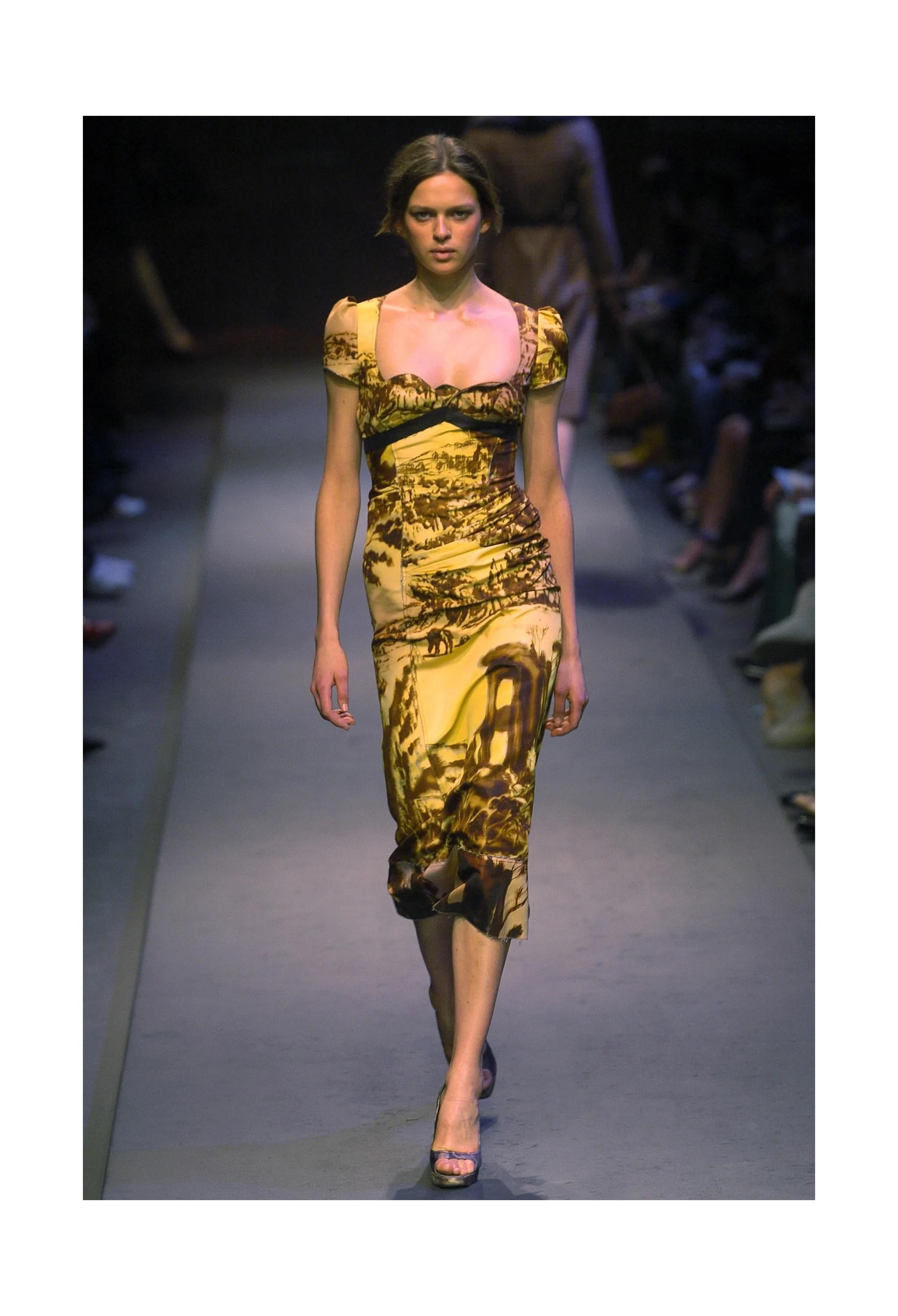 Resurrection Vintage a le plaisir de vous proposer une robe vintage Prada jaune et marron de la collection Automne 2004, avec un imprimé graphique de paysage, un décolleté en cœur, une taille empire, des manches courtes bouffantes, une fermeture