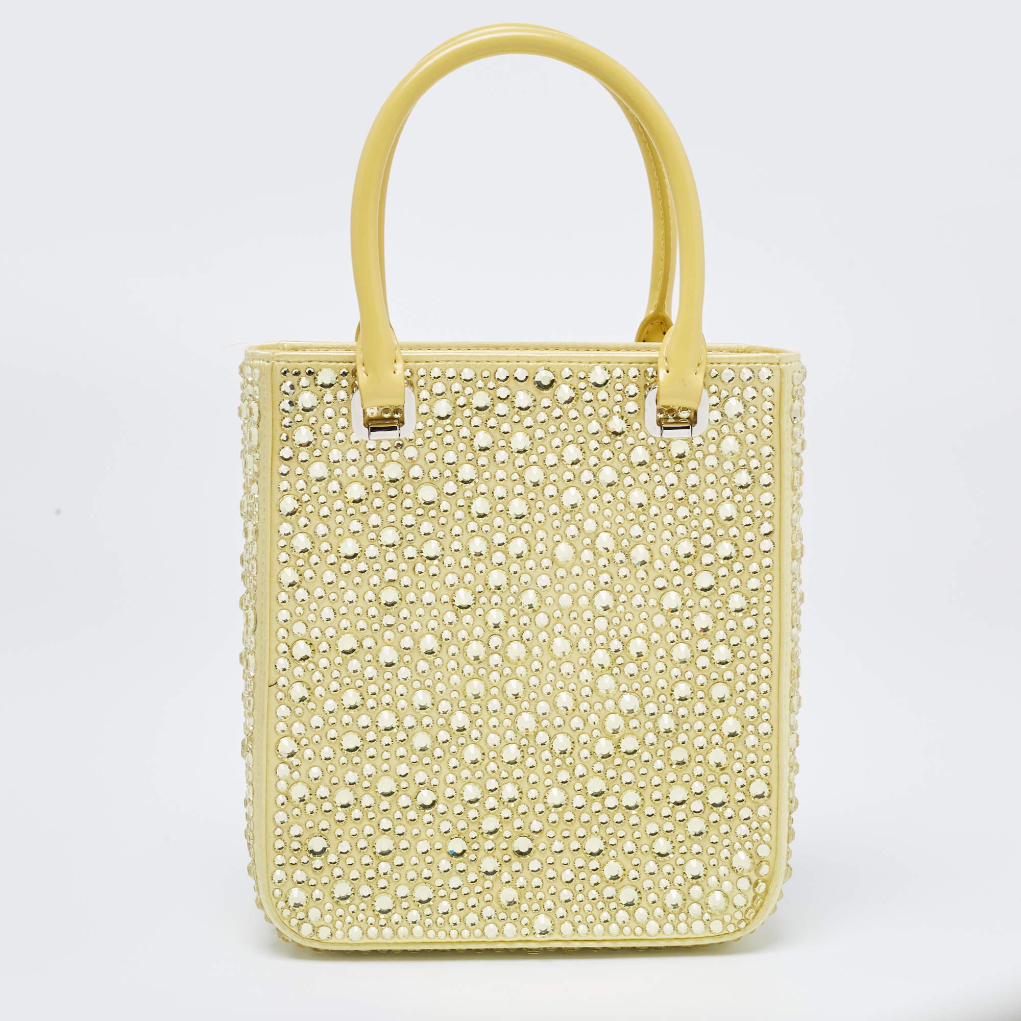The Prada tote is a luxurious and eye-catching accessory. Crafted from vibrant yellow satin, it features intricate crystal embellishments that add a touch of glamour and sophistication. With its compact size and tote design, this bag seamlessly