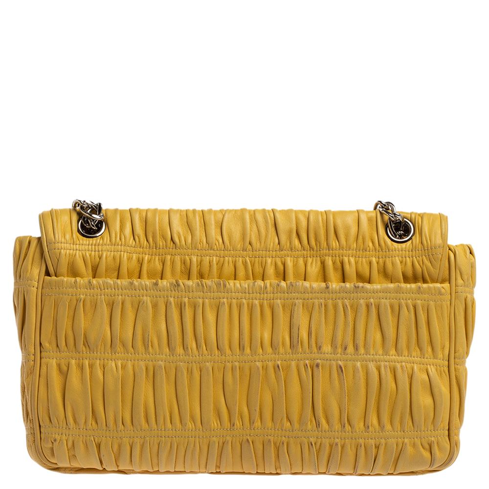 Elevate your style with this gorgeous shoulder bag by Prada. Crafted from yellow Nappa Gaufre leather, the bag features silver-tone hardware. It has a simple lock on the flap and a well-lined interior. This bag is complete with a chain