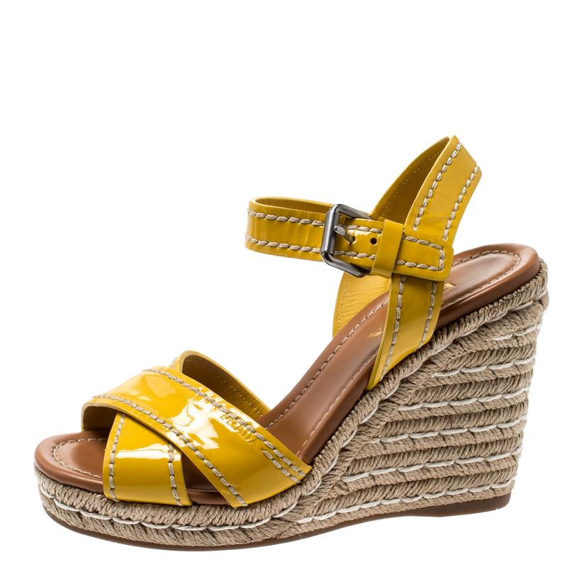Look you casual best as you step out in these patent leather sandals from Prada. These bright yellow sandals feature cross front straps, buckled ankle straps, and espadrille wedge heels. They will offer maximum style and comfort.

Includes: The