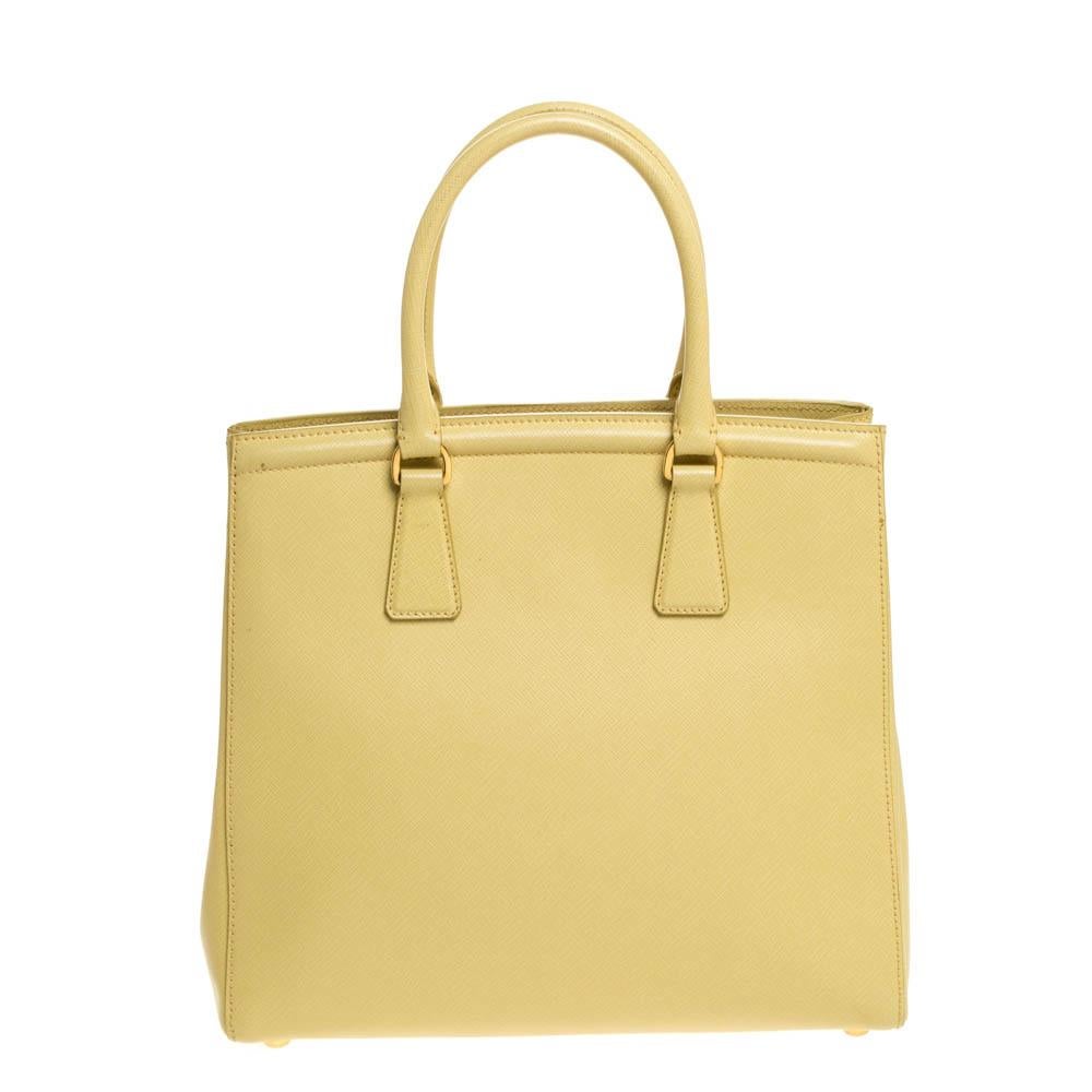 Masterfully created, this chic Prada Parabole tote is a style icon. Designed in a Saffiano Lux leather body, it exudes style and class in equal measures. This delightful yellow-hued piece is held by two top handles and equipped with a spacious nylon