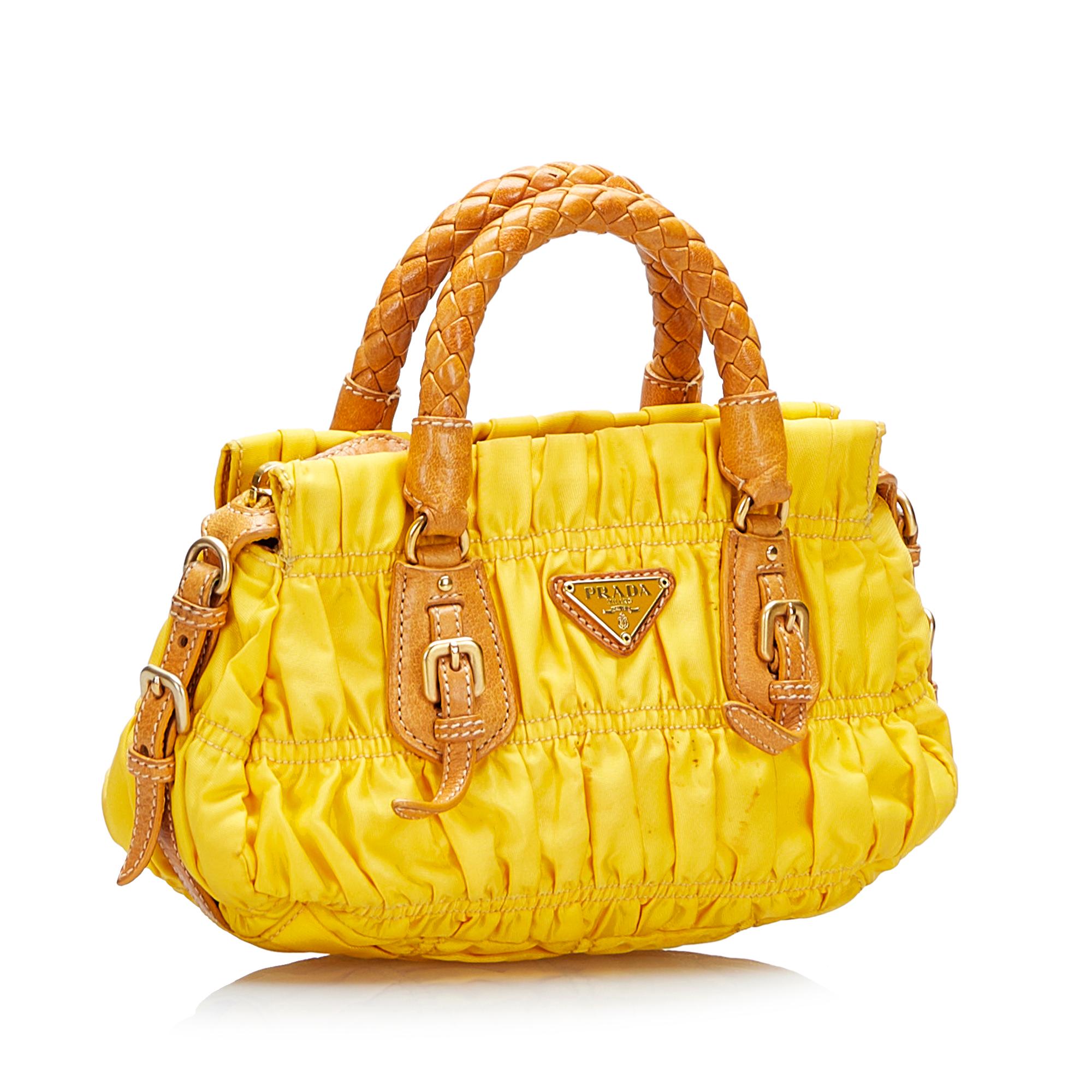Product Details: Yellow Prada Tessuto Gaufre Satchel Bag. This satchel features a gathered nylon body, rolled leather handles, a detachable flat leather strap, an open top with a magnetic snap button closure and interior zip and slip pockets. 4.1