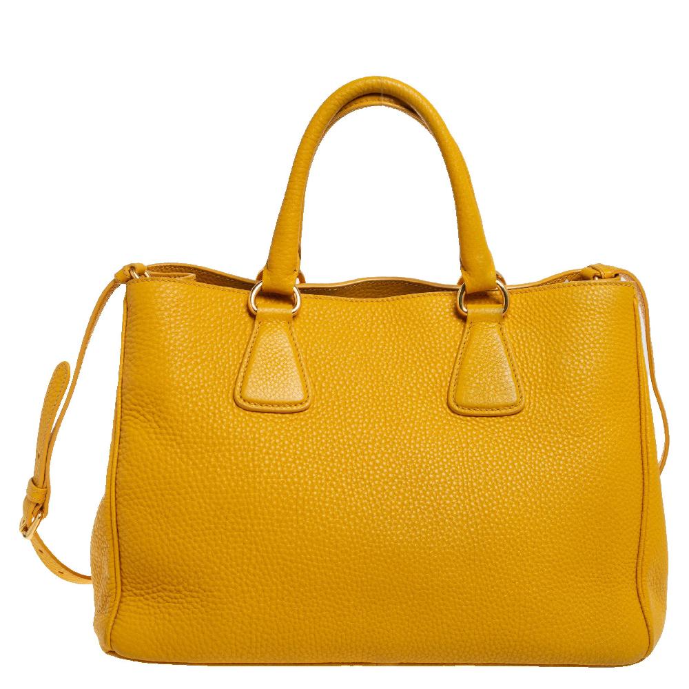 This sleek and spacious Prada tote is luxurious enough to elevate any look. Flaunt your unique taste in fashion with this yellow tote that comes crafted from Vitello Daino leather and designed with dual top handles. Equipped with a spacious nylon
