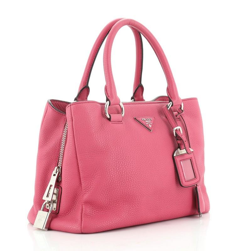 This Prada Zip Around Convertible Tote Vitello Daino Medium, crafted in pink vitello daino leather, features dual rolled leather handles, Prada logo at the center, and silver-tone hardware. It opens to a black fabric interior with a center zip