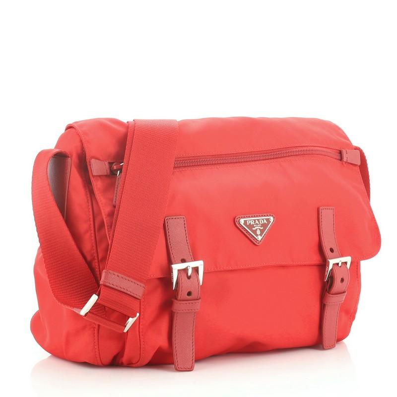 This Prada Zip Buckle Messenger Bag Tessuto Medium, crafted in red tessuto, features an adjustable shoulder strap, exterior front zip pocket on flap, exterior back zip pocket, and silver-tone hardware. Its buckle closure opens to a red fabric