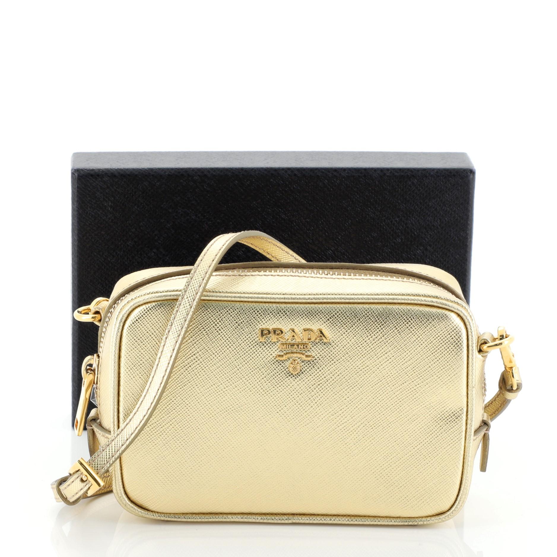 This Prada Zip Crossbody Bag Saffiano Leather Mini, crafted in metallic gold saffiano leather, features gold-tone hardware, long leather adjustable straps, signature Prada logo and gold-tone hardware. Its zipped closure opens to a neutral fabric