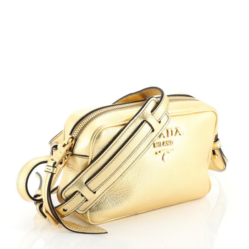 This Prada Zip Crossbody Bag Vitello Phenix Mini, crafted in metallic gold leather, features an adjustable leather strap, signature Prada logo, and gold-tone hardware. Its zip closure opens to a black fabric interior with slip pockets. 

Condition: