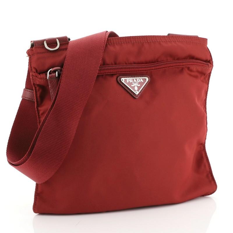 This Prada Zip Messenger Bag Tessuto Medium, crafted from red tessuto, features an adjustable shoulder strap and silver-tone hardware. Its zip closure opens to a red nylon interior. 

Condition: Great. Minor wear in interior, scratches on
