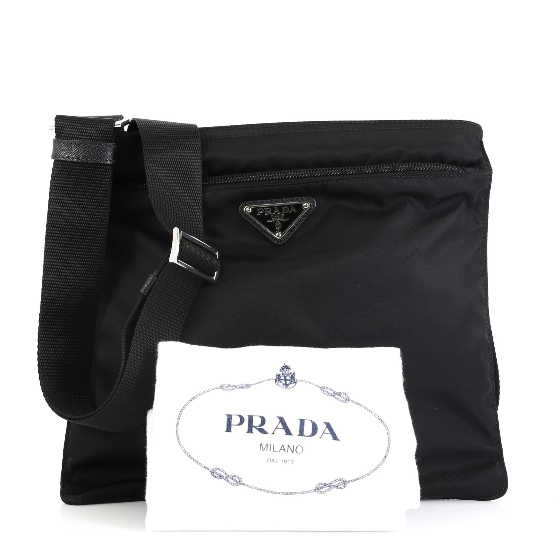 This Prada Zip Messenger Bag Tessuto Medium, crafted from black tessuto, features adjustable shoulder strap, exterior zip pocket, and silver-tone hardware. Its top zip closure opens to a black nylon interior. 

Condition: Excellent. Minor scuffs on
