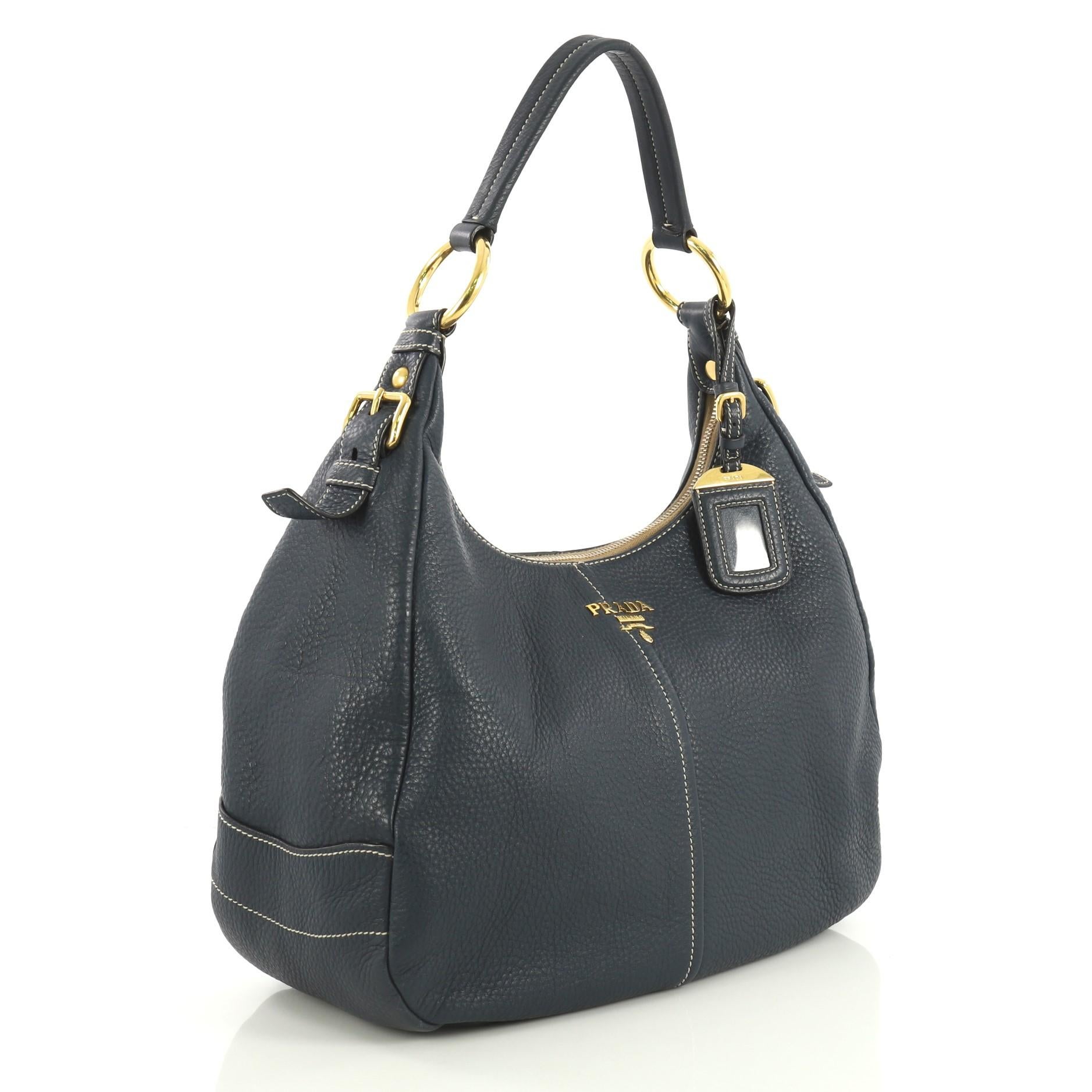 This Prada Zip Top Hobo Vitello Daino Medium, crafted from blue vitello daino leather, features a flat leather handle, raised Prada logo and gold-tone hardware. Its zip closure opens to a gold fabric interior with zip and snap pockets. 

Estimated