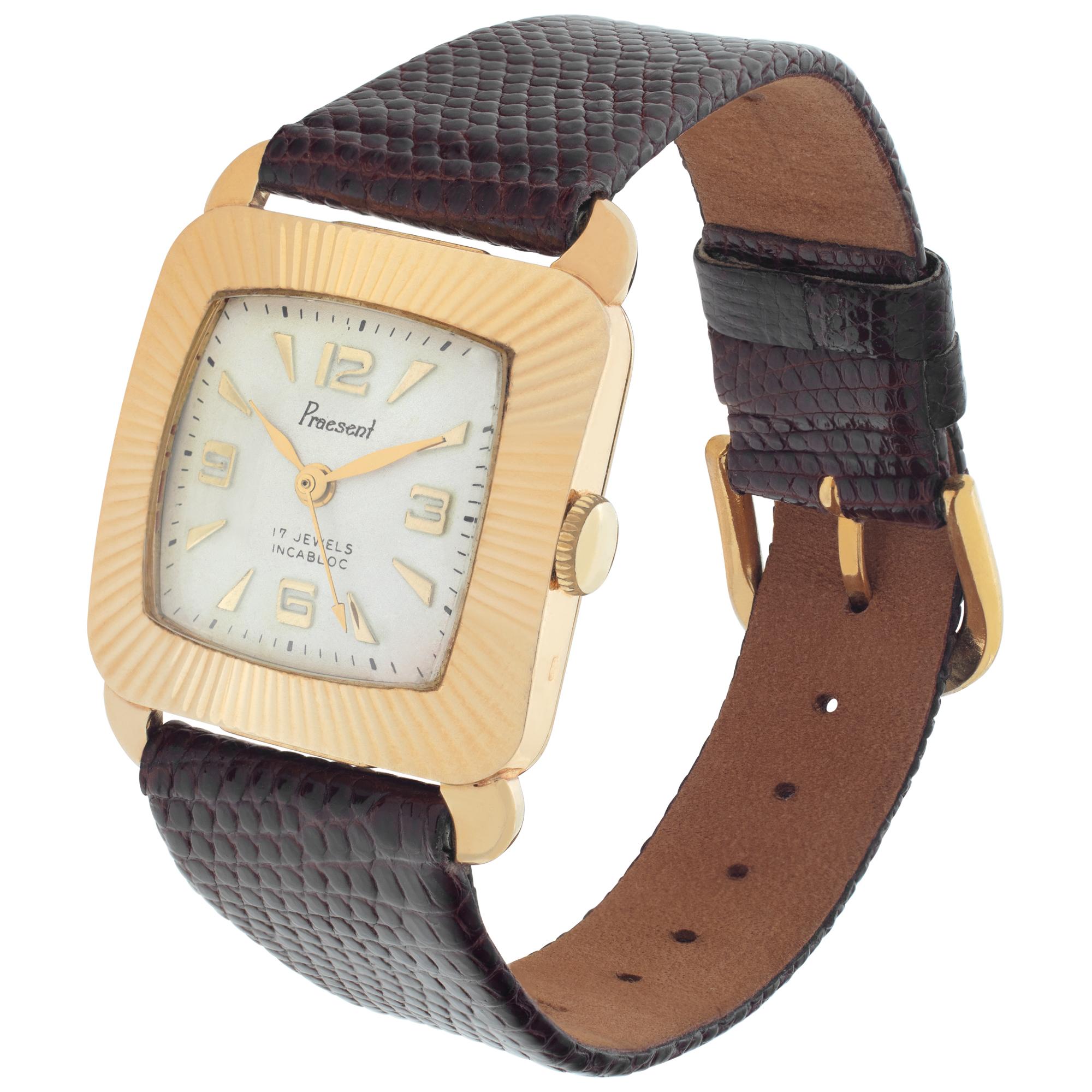 Praesent Incabloc in 18k with textured fluted bezel, white dial set with applied Arabic and sticks markers on a lizard band with a gold fill tang buckle. Manual  17 Jewel movement w/center sweep seconds. Circa 1960s. Fine Pre-owned Praesent Watch.