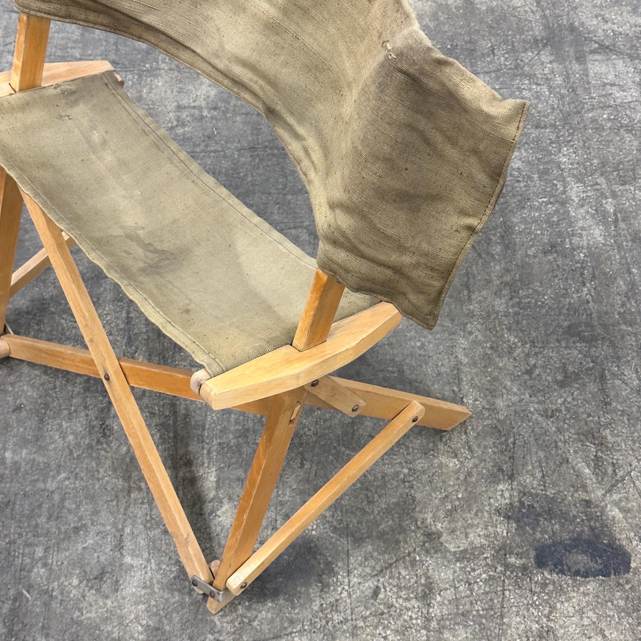 c. 1960s. Chaise pliante avec structure en bois et harnais en toile. Le dossier de la chaise est un sac de transport dans lequel la chaise entière se range. Il s'agit apparemment d'un article promotionnel pour les caméras Petri. 