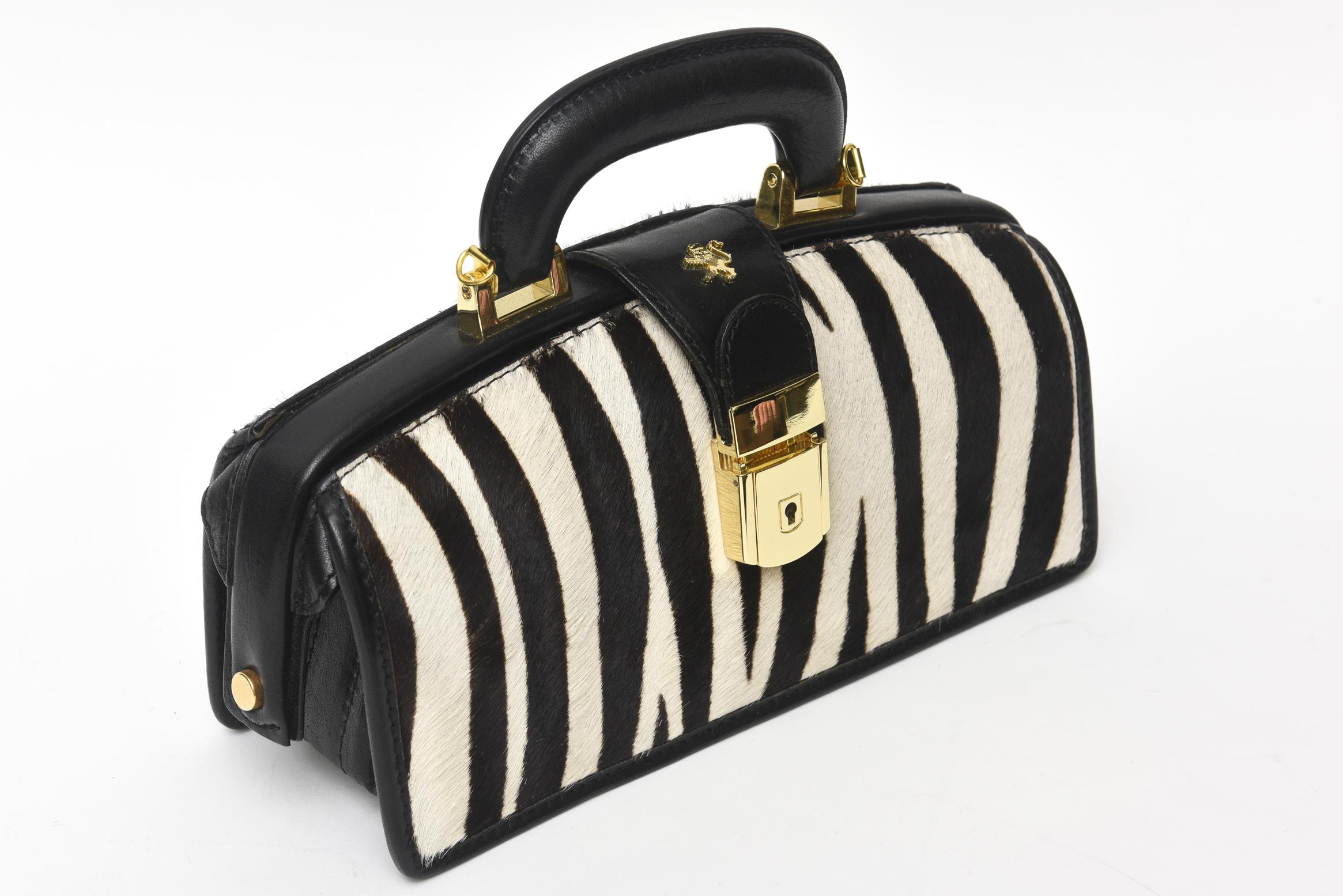 This gorgeous vintage Italian zebra pony hair mini doctor's bag handbag has gold plated hardware with a key and a special lock. The handle is black leather with a stunning gold leather interior. There is also a light inside to view the beautiful